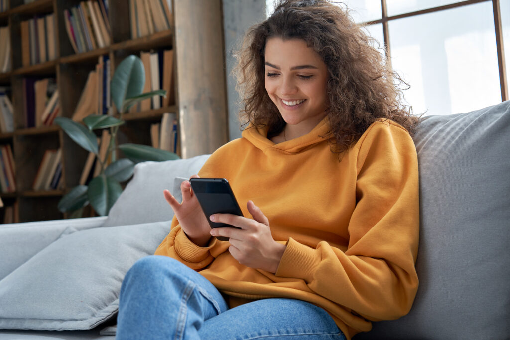 oung adult using a smartphone, representing Millennial and Gen Z loyalty in mobile banking.